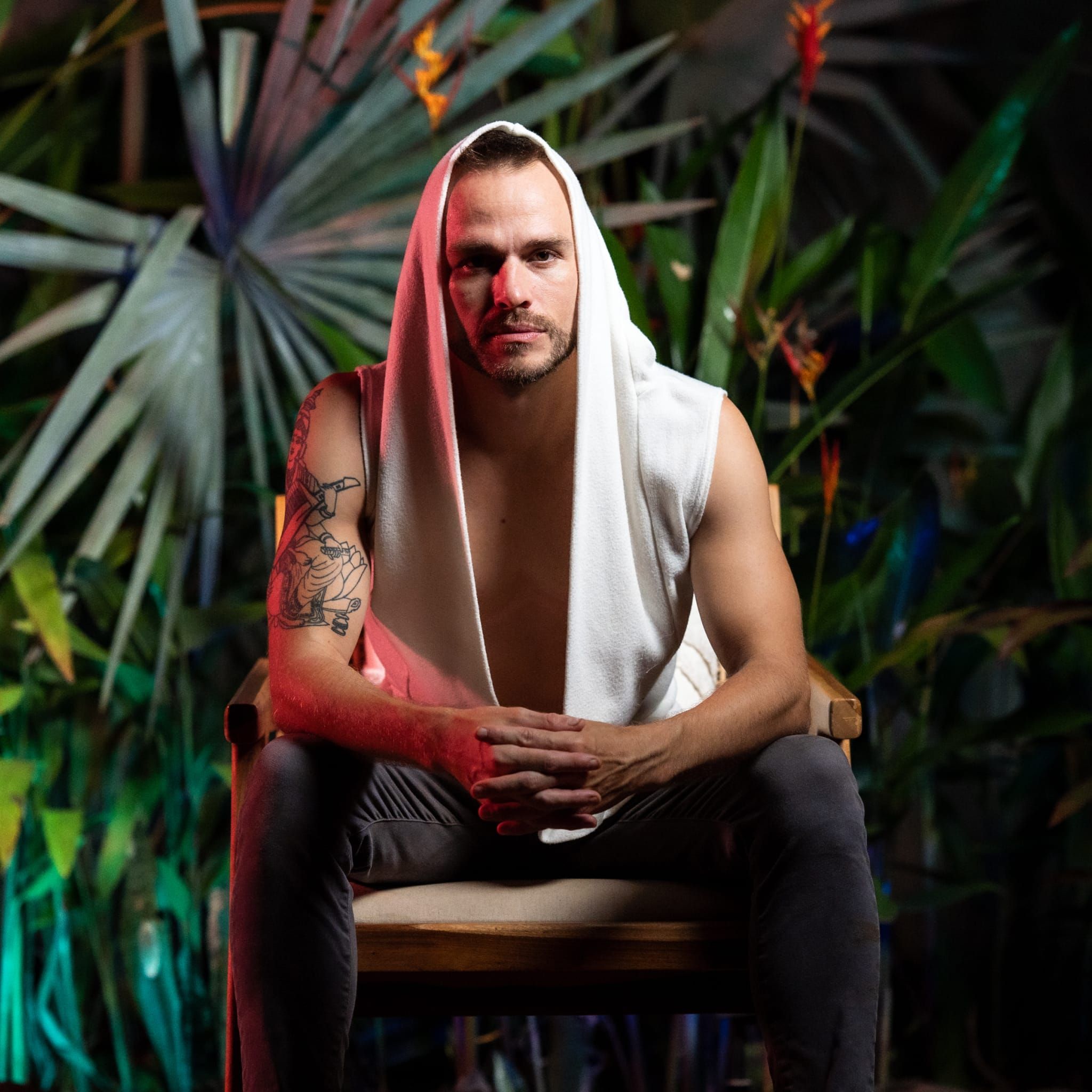 Steffen, hooded, seated before a wall of palms