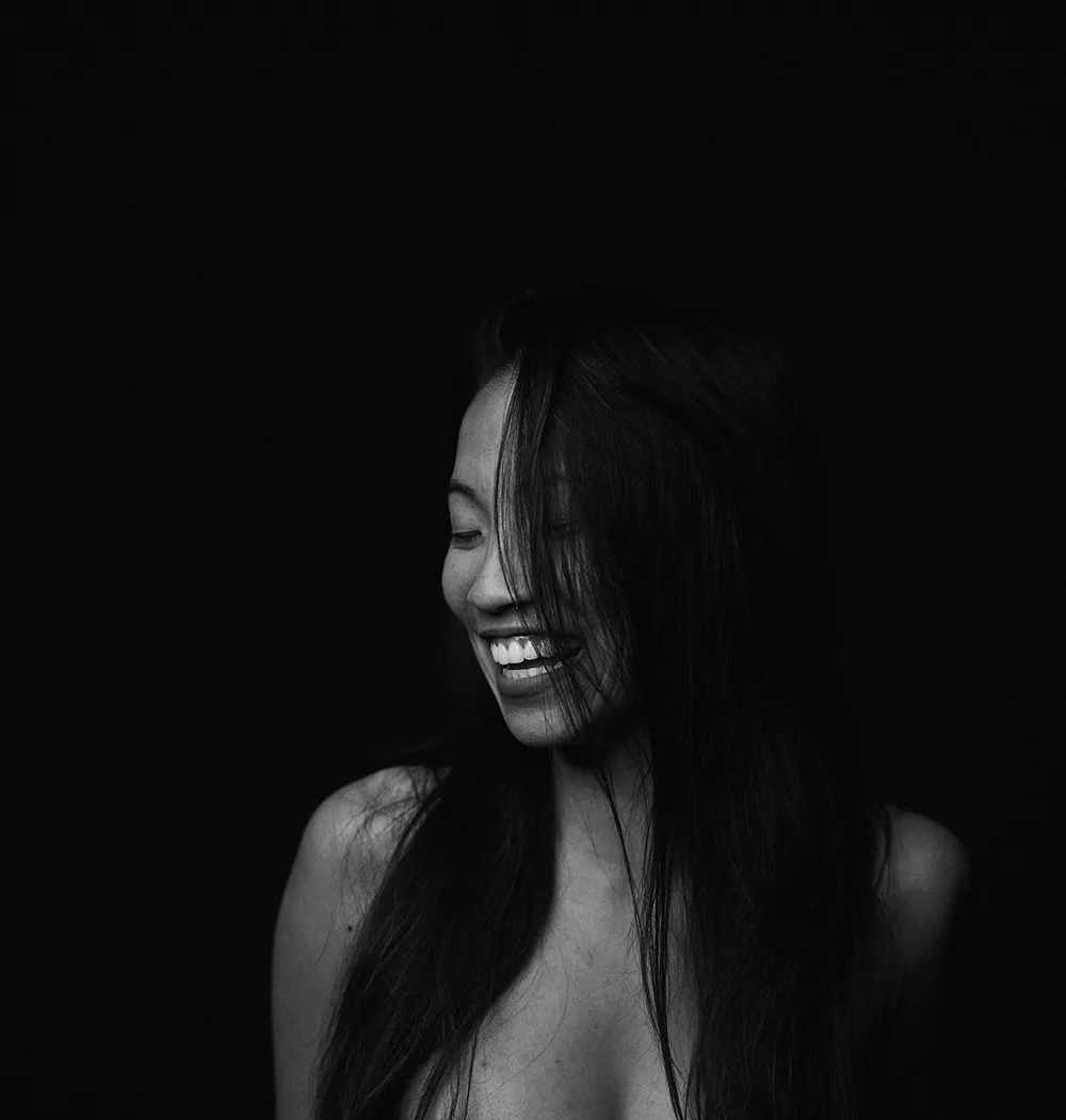 A woman laughing, most of her face lost to shadow