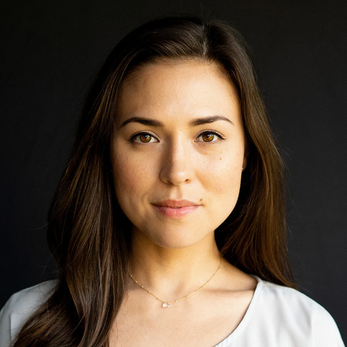 A woman looking straight into the lens against a dark ground